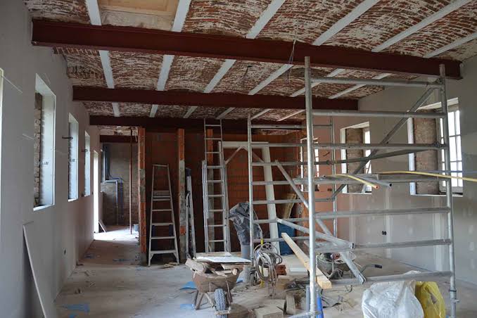 Renovatie-interieur met bakstenen plafond, steigers, ladders en bouwmaterialen in een lege gang.